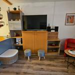 Wohnzimmer mit Fernseher, rotem Sessel und Holzboden.