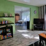 Living room with TV, bookcase, and view into dining room. Green walls and wooden floor.