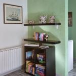 A room with green walls, a bookcase, and wall pictures of ships.