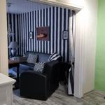 Black sofa with cushions against striped wall. Mirror and wooden table in background.