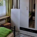 Bedroom with bed, wardrobe, and window with curtains.