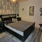 Bedroom with bed, nightstand, chair, and decorative wall elements.