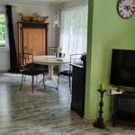 Dining area with round table and chairs. TV and wall clock are visible.
