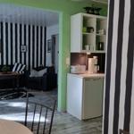 Living area with black-and-white striped wall and small kitchen with refrigerator.
