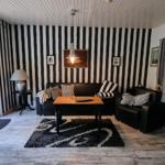 Living room with black-and-white striped walls, sofa, armchair, and wooden table.