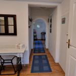 Hallway with blue rugs, wooden floor, and white walls. Door and window are visible.