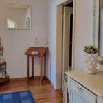 Entrance area with mirror, table, vase, and wooden floor.