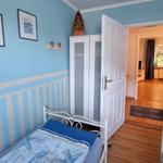 Bedroom with blue walls, bed, and wardrobe. Corridor to next room.