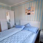 Bedroom with striped walls, white bed, and wardrobe.