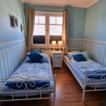 Two single beds with blue bedding, wooden floor, and window with curtains.
