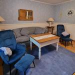 Living room with sofa, two blue chairs, and wooden table on rug.