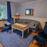 Living room with sofa, two chairs, table, and window with view of greenery.