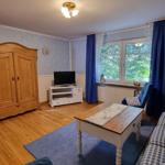 Living room with wooden floor, sofa, table, and TV. Window with blue curtains.