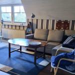 Living room with sofa, table, and chair. Window and wall paneling visible.