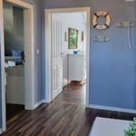 Hallway with blue walls, wooden floor, and nautical decor. Doors lead to bedroom and bathroom.