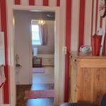 Kitchen with view into bedroom. Red striped wall, wooden furniture, and window with curtain.