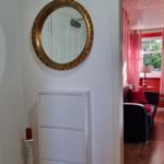 Entryway with mirror and cabinet. View into living room with sofa and window.