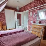 Bedroom with bed, wardrobe, and dressing table. Red-and-white wallpaper. Skylight with roller shutter.