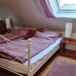 Bedroom with skylight, bed with striped bedding, and two nightstands.