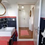 Bathroom with sink, mirror, and towel rack. Hallway to living area with wooden floor.