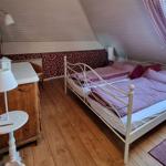 Double bed with striped bedding, wooden floor, and window with curtains.