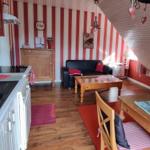 Kitchen, living, and dining area with red striped walls and wooden furniture.