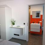 Bedroom with wardrobe and storage space. View into the bathroom.