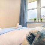 Schlafzimmer mit Bett, Fenster und Vorhängen. Auf dem Bett liegen Handtücher.