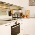 Küche mit Edelstahlarbeitsplatte, Backofen, Mikrowelle und Spüle.