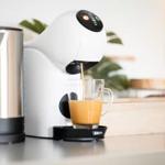 Eine Kaffeemaschine gießt Kaffee in ein Glas auf einer Arbeitsfläche.