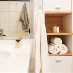 Bad mit Waschbecken, Spiegel, Handtuch und Handtüchern auf Holzregal.