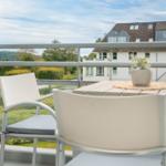 Terrasse mit Tisch und Stühlen. Blick auf Wohnhaus und grüne Landschaft.