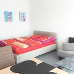 Schlafzimmer mit Bett, Sofa und Esstisch. Wandbild mit Leuchtturm.