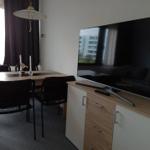 Essbereich mit Tisch, Stühlen und Fernseher auf Sideboard.