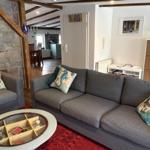 Wohnzimmer mit grauem Sofa, runden Tisch und Steinwand. Blick in die Küche.