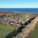 Aerial view of holiday park near sea with forest and fields.