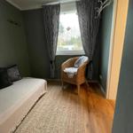 Schlafzimmer mit Bett, Stuhl und Fenster mit Vorhängen.