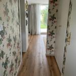 Flur mit Holzboden und floraler Tapete führt zu einem Fenster mit Blick nach draußen.