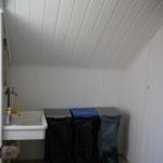 Small room with sink and three trash bins with black bags.