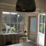 Indoor space with window and door to garden. View of a terrace and fence.