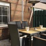 Terrace with table, chairs, and heater against brick wall
