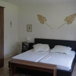 Bedroom with double bed, nightstands, and wardrobe. Wall decor with leaf motifs.