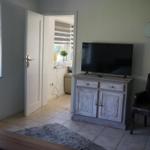 Living area with TV, leather chair, and window. Door leads to adjacent room.