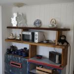 Kitchen area with microwave, toaster, and decorative items on wooden shelves.