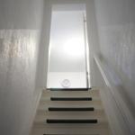 Staircase with white walls and black tread mats leads to a door.