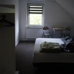 Room with bed, table, two chairs, and window with blinds.