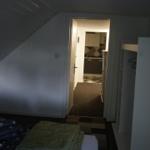 Bedroom with view into kitchen and closet. Sloped ceiling visible.