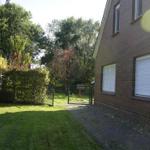 Backyard with lawn, hedge, and gate leading to a brick house with windows.