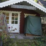 House with white doors and red walls, surrounded by plants and a green cover.
