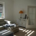 Living room with sofa, coffee table, and cabinet. Door leads to the kitchen.